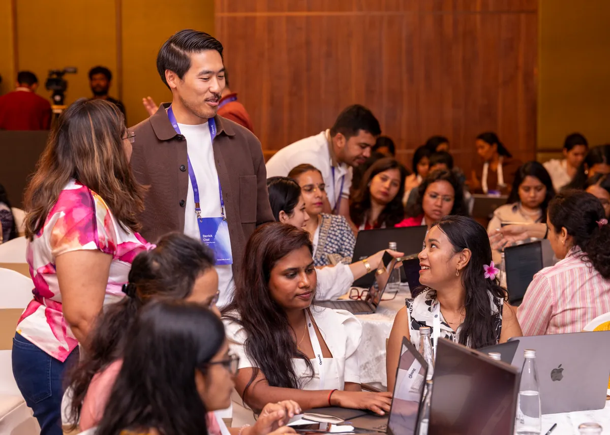 Derrick Choi talking with participants working on laptops at a workshop.